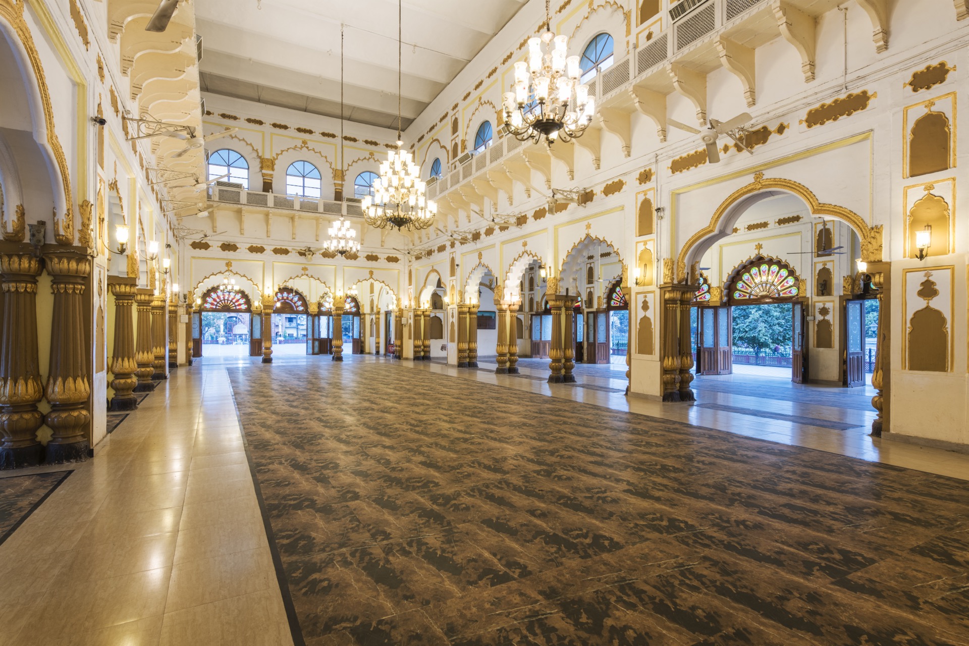 Wide view of the grand hall with arched balcony and chandeliers
